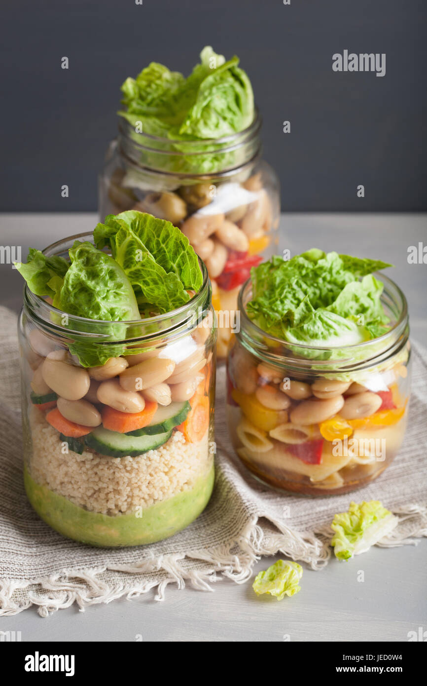 vegan couscous and pasta salad in mason jars with vegetables beans