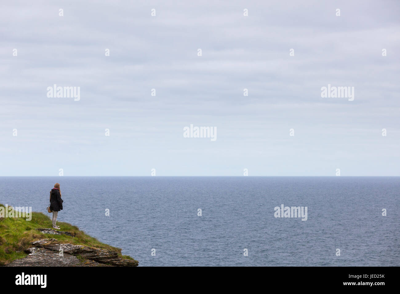 Cornwall, uk, lone women on cliff rock face looking out to sea Stock Photo