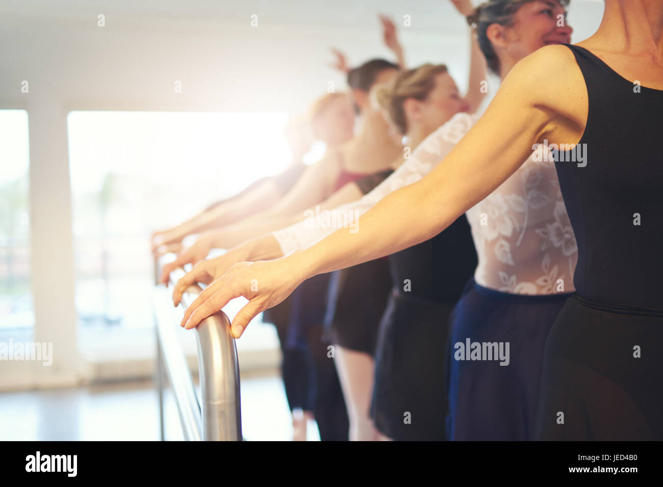Hands of unrecognizable mature group of women holding handrail while performing a ballet in class together. Stock Photo