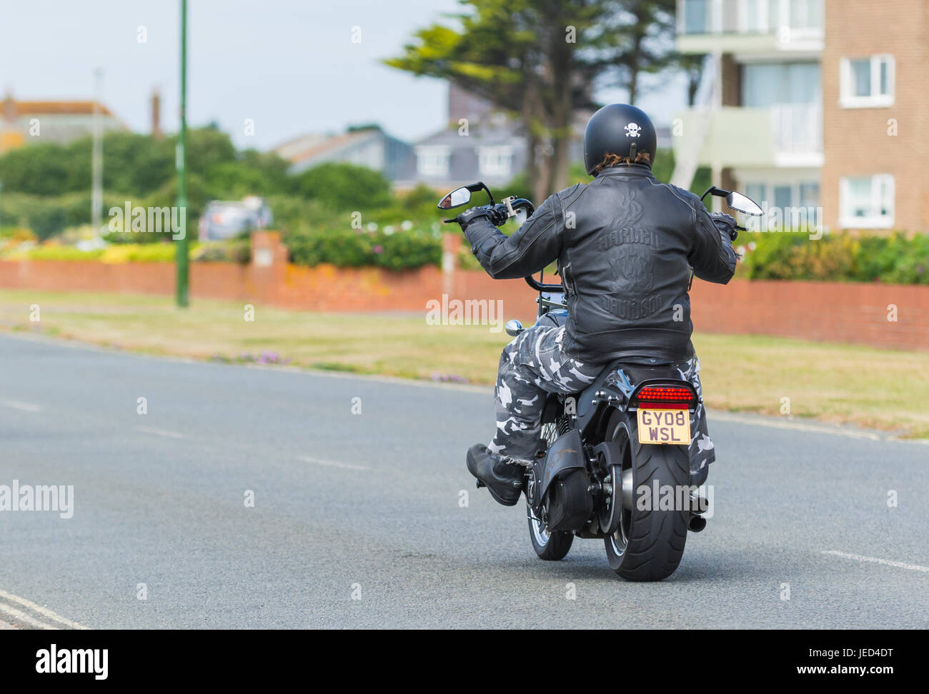 Motorcyclist wearing a Harley Davidson jacket riding on a Harley Davidson motorcycle. Harley Davidson bike. Stock Photo