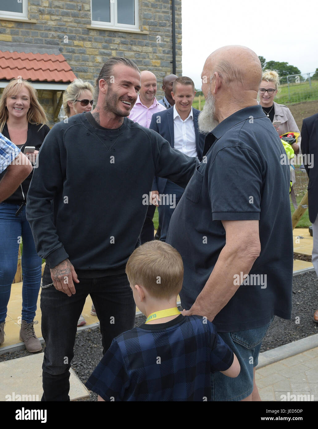 David Beckham and Michael Eavis outside a completed house in a housing