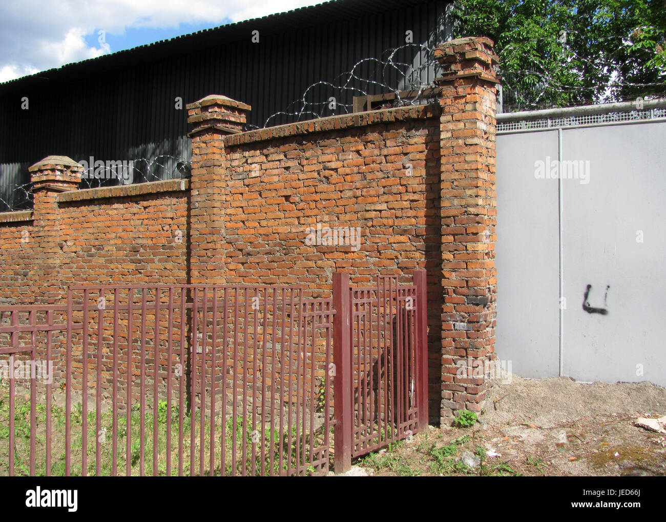 Metal fence, brick wall with barbed wire Stock Photo