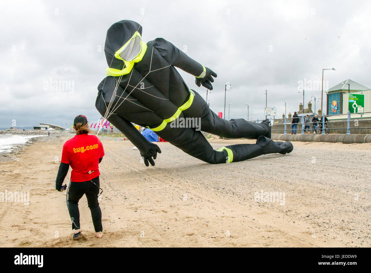 Morecambe, Lancashire, UK. 24th June, 2015. UK Weather. Strong winds on the coast as Kite Flyers struggle to launch and retrieve their kites.The Midland Hotel Catch The Wind Kite Festival is an annual event on Morecambe seafront, when for the whole day the skies are full of the most spectacular shapes, colours and creations. Credit:MediaWorldImages/AlamyLiveNews Stock Photo