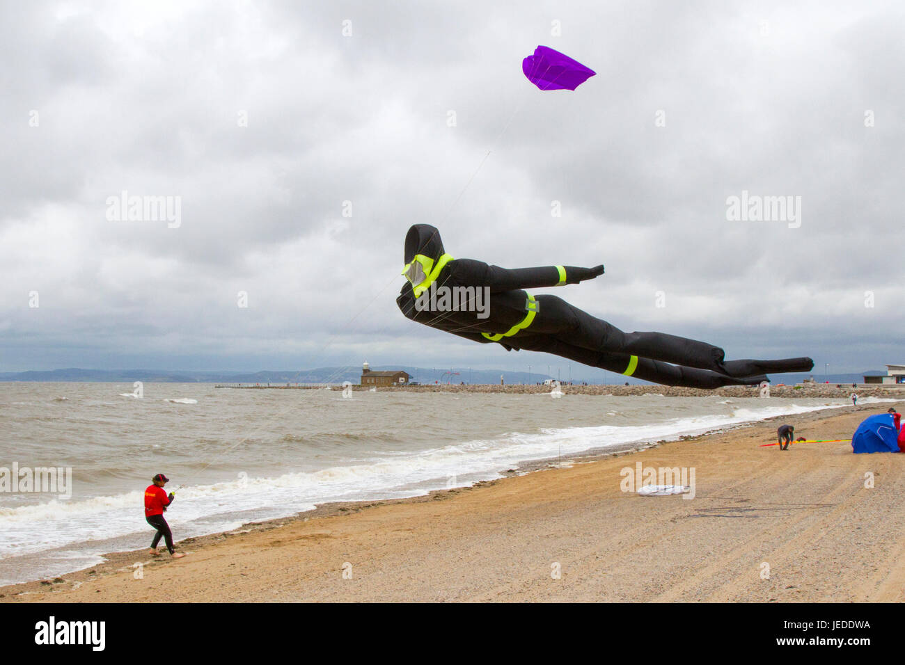 Morecambe, Lancashire, UK. 24th June, 2015. UK Weather. Strong winds on the coast as Kite Flyers struggle to launch and retrieve their kites.The Midland Hotel Catch The Wind Kite Festival is an annual event on Morecambe seafront, when for the whole day the skies are full of the most spectacular shapes, colours and creations. Credit:MediaWorldImages/AlamyLiveNews Stock Photo