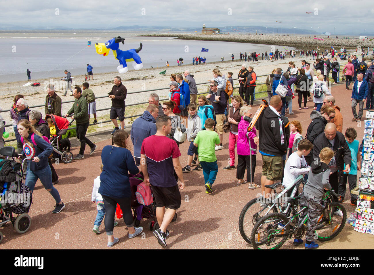 People watching Kite Festival in Morecambe, Lancashire, UK. June, 2015. UK Weather. Strong winds on the coast as Kite Flyers struggle to launch and retrieve their kites.The Midland Hotel Catch The Wind Kite Festival is an annual event on Morecambe seafront, when for the whole day the skies are full of the most spectacular shapes, colours and creations. Credit:MediaWorldImages/AlamyLiveNews Stock Photo