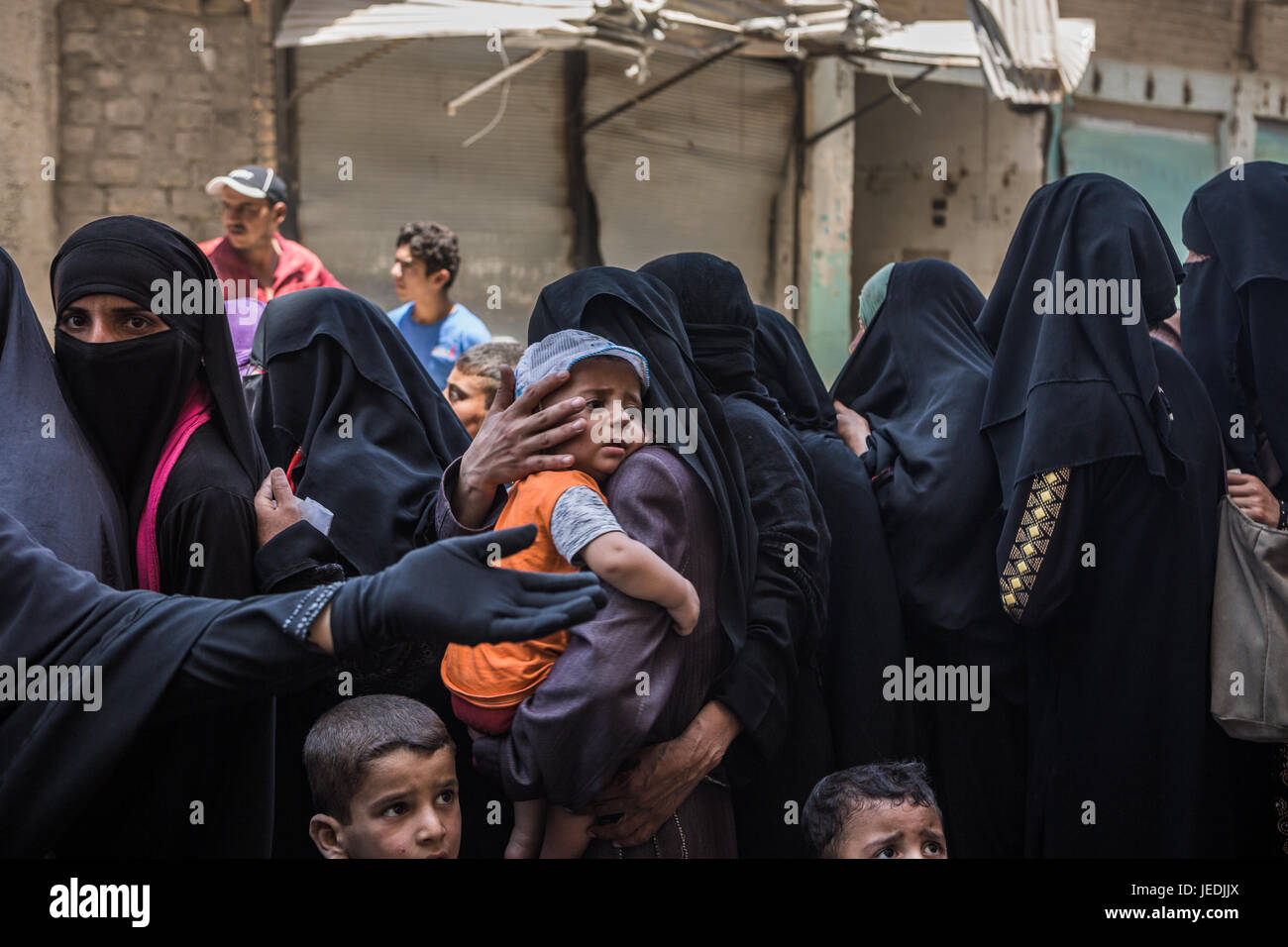 Civilians line up for an aid distribution in the al-Mansur neighbourhood in western Mosul, Iraq, 24 June 2017. Photo: Andrea DiCenzo/dpa Stock Photo