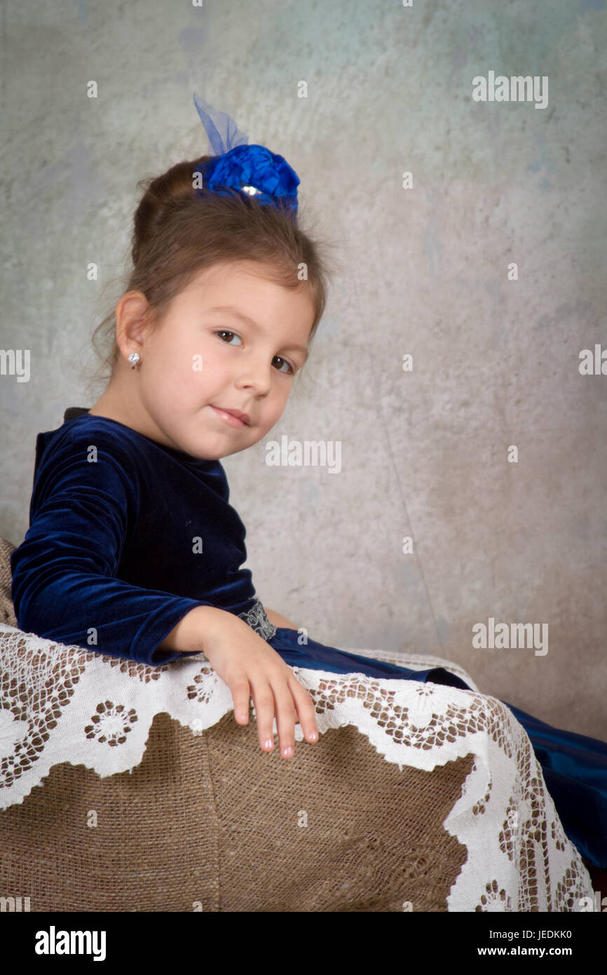 beautiful little girl princess in blue dress sitting on white chair and ...