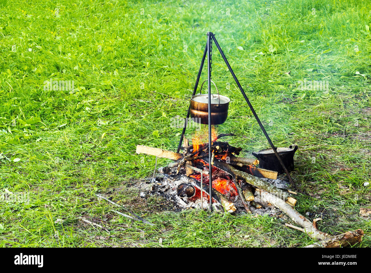 Bowler on a tripod over a fire, cooking food in a field tent camp Stock Photo
