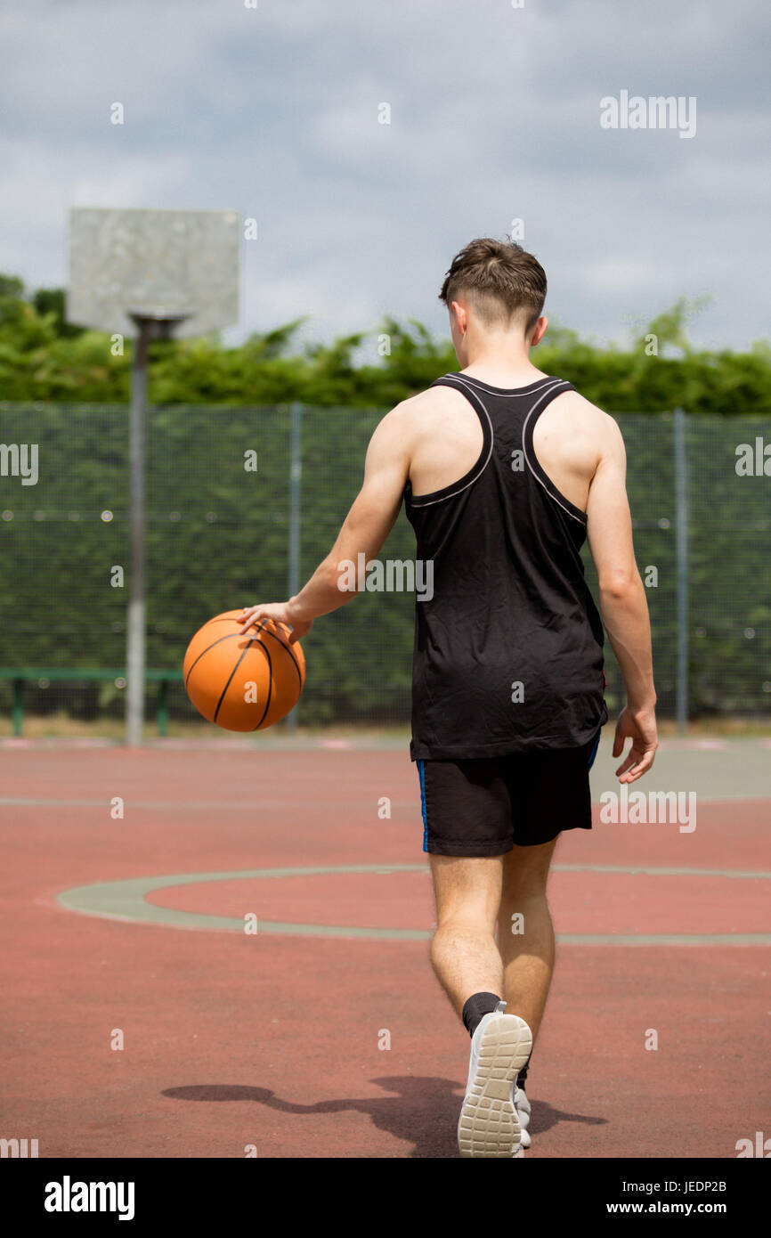 Teenage boy bouncing a basketball on a court Stock Photo Alamy