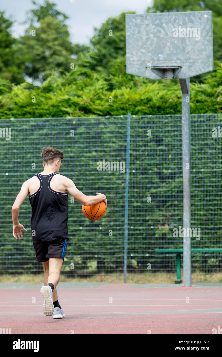 Teenage boy bouncing a basketball on a court Stock Photo Alamy