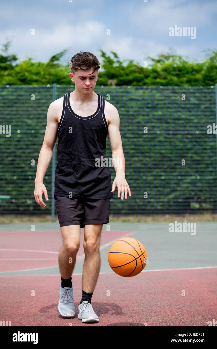 Teenage boy bouncing a basketball on a court Stock Photo Alamy