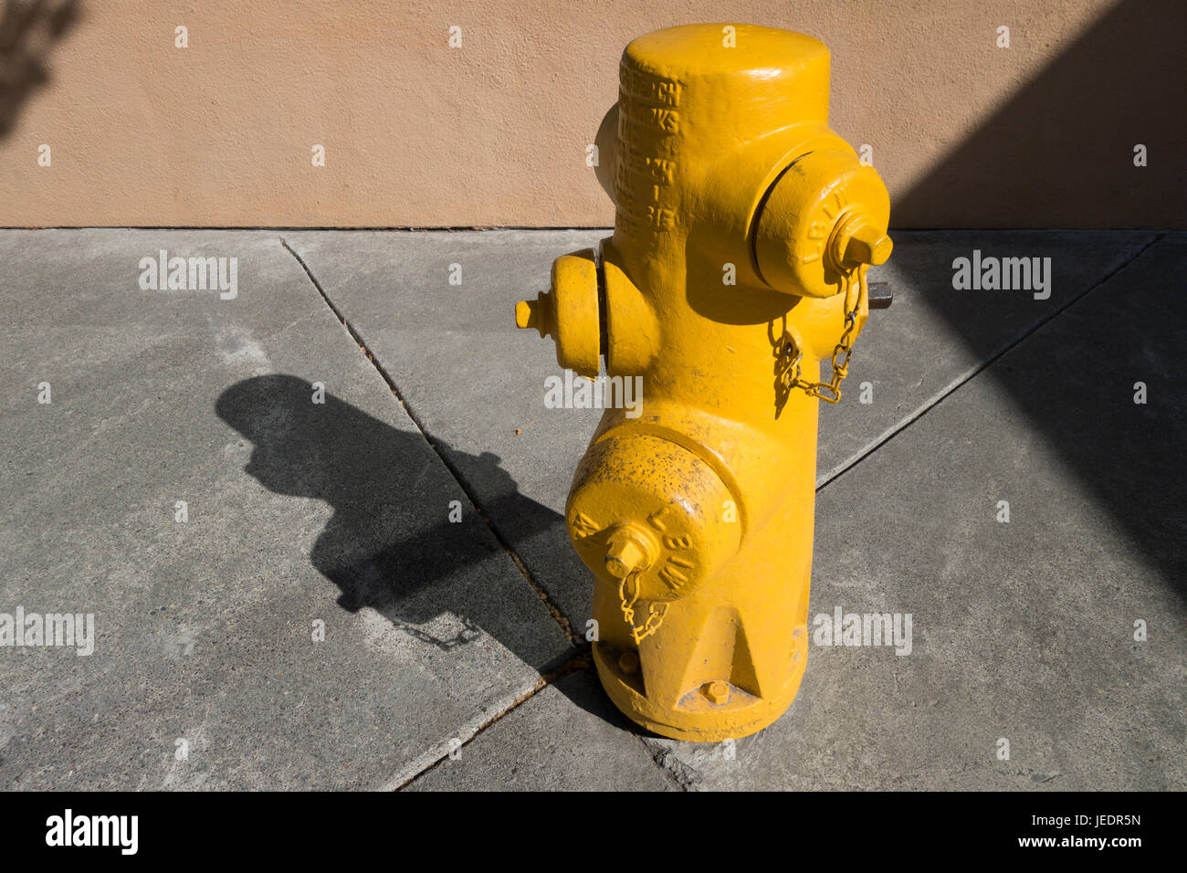 yellow hydrant on a sidewalk on a sunny day Stock Photo