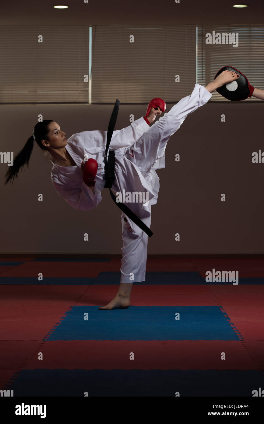 Young Woman Practicing Her Karate Moves - White Kimono - Black Belt Stock Photo