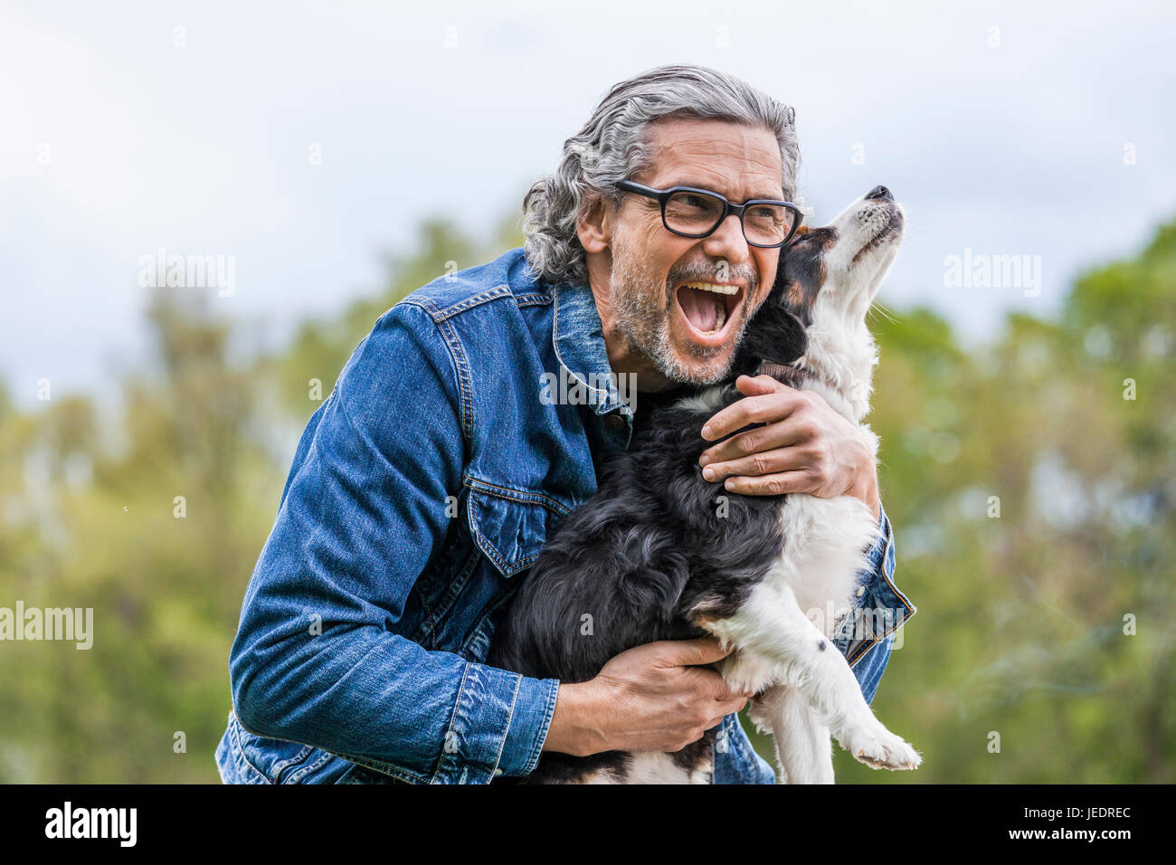 Portrait of happy senior man cuddling his dog Stock Photo