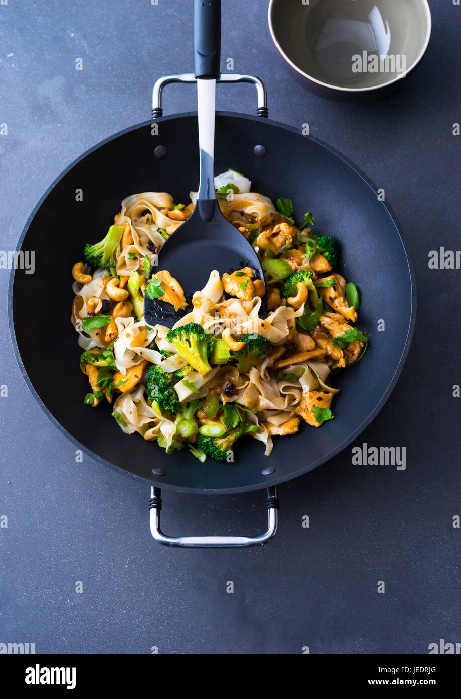 Asiatisch gebratene Nudeln mit Huhn, Brokkolie und Cashewkerne im Wok Stock Photo