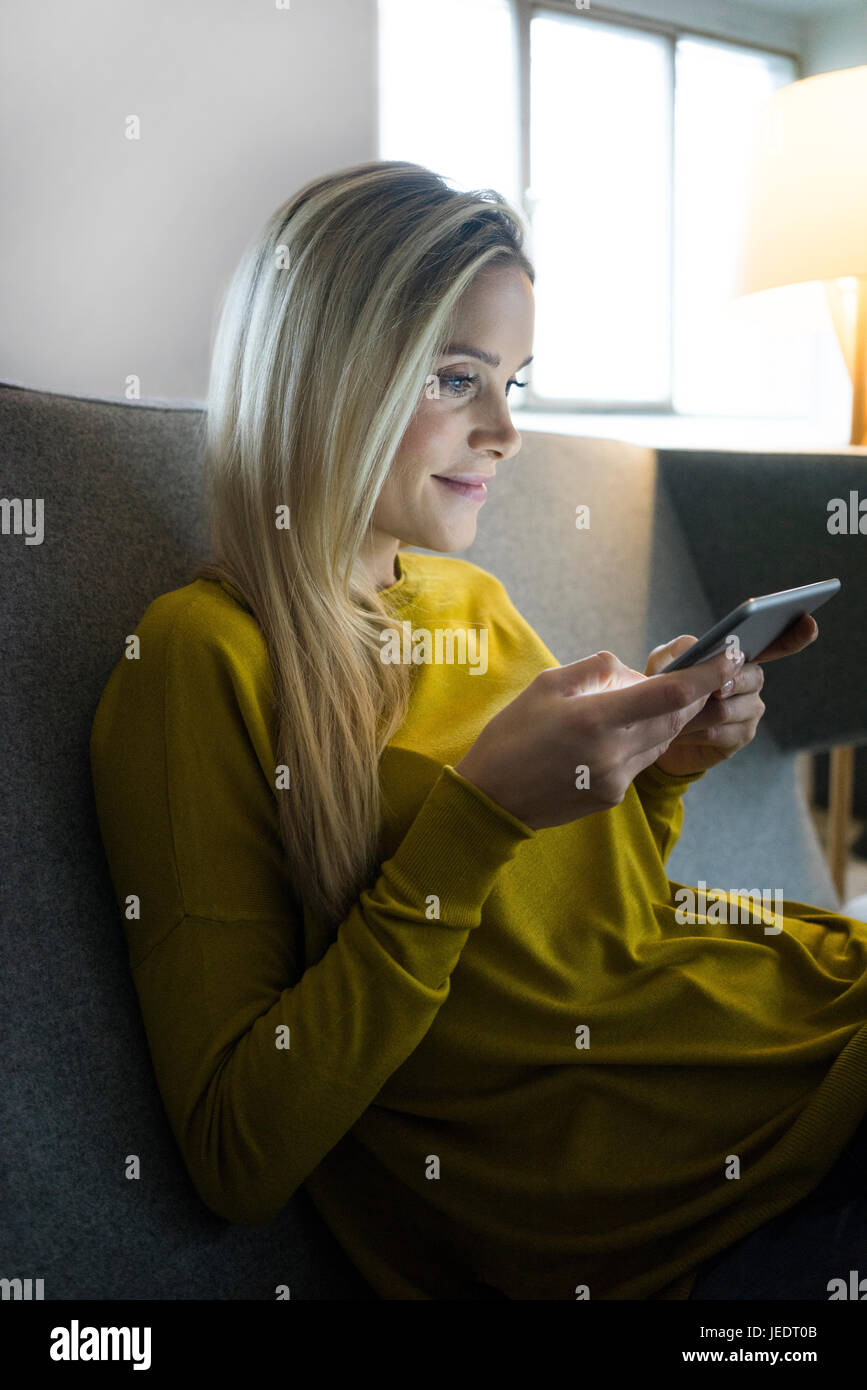 Portrait of woman sitting on couch using mini tablet Stock Photo - Alamy