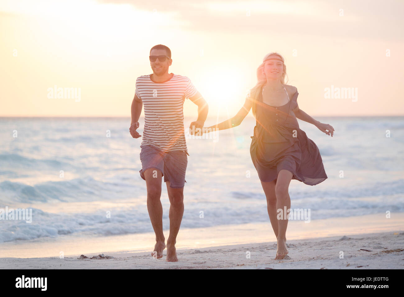 Young couple running on the beach, holding hands Stock Photo - Alamy