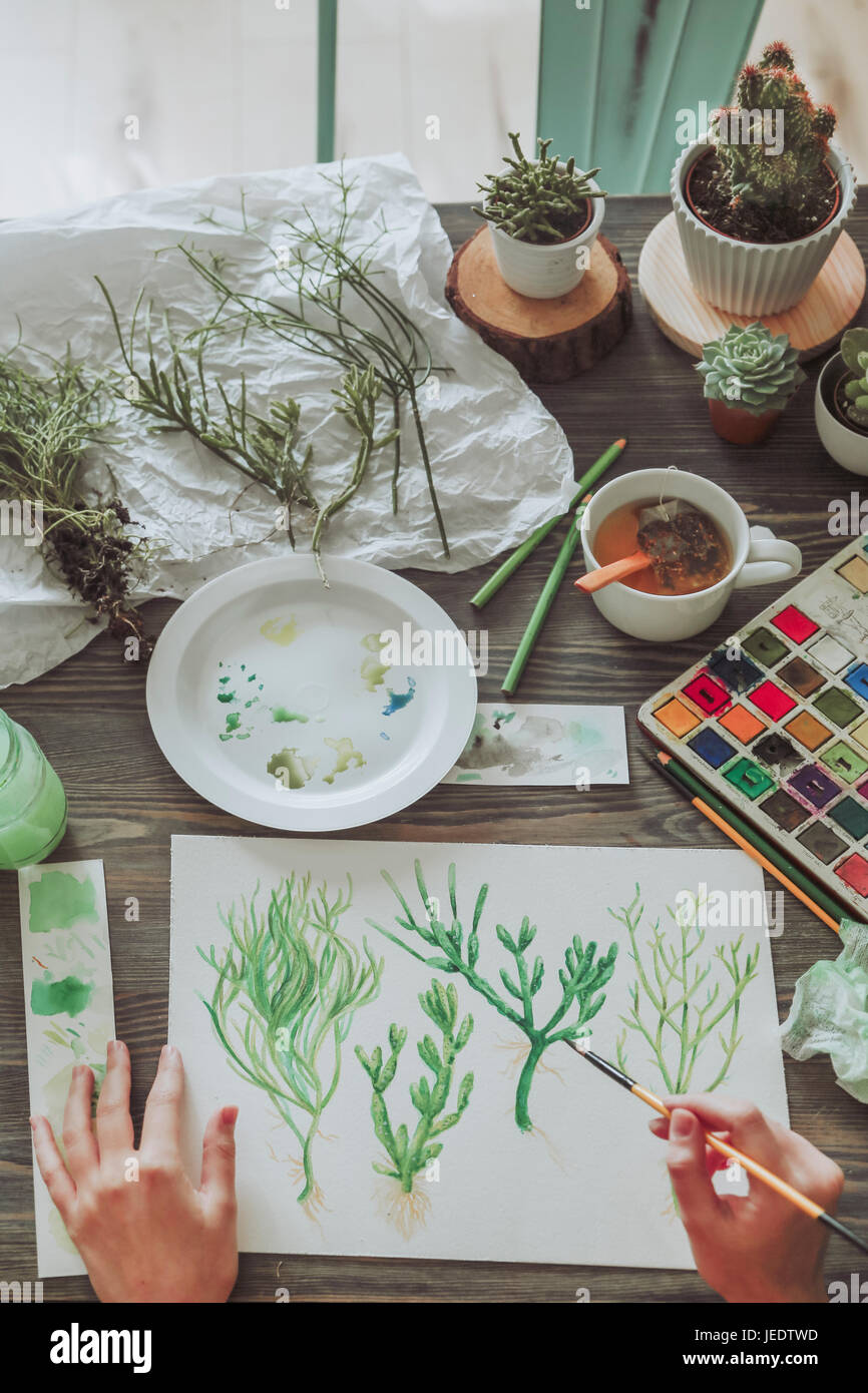 Young woman painting plants with water colors Stock Photo