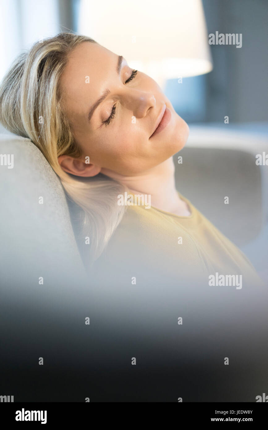 Portrait of blond woman with eyes closed relaxing on couch Stock Photo ...