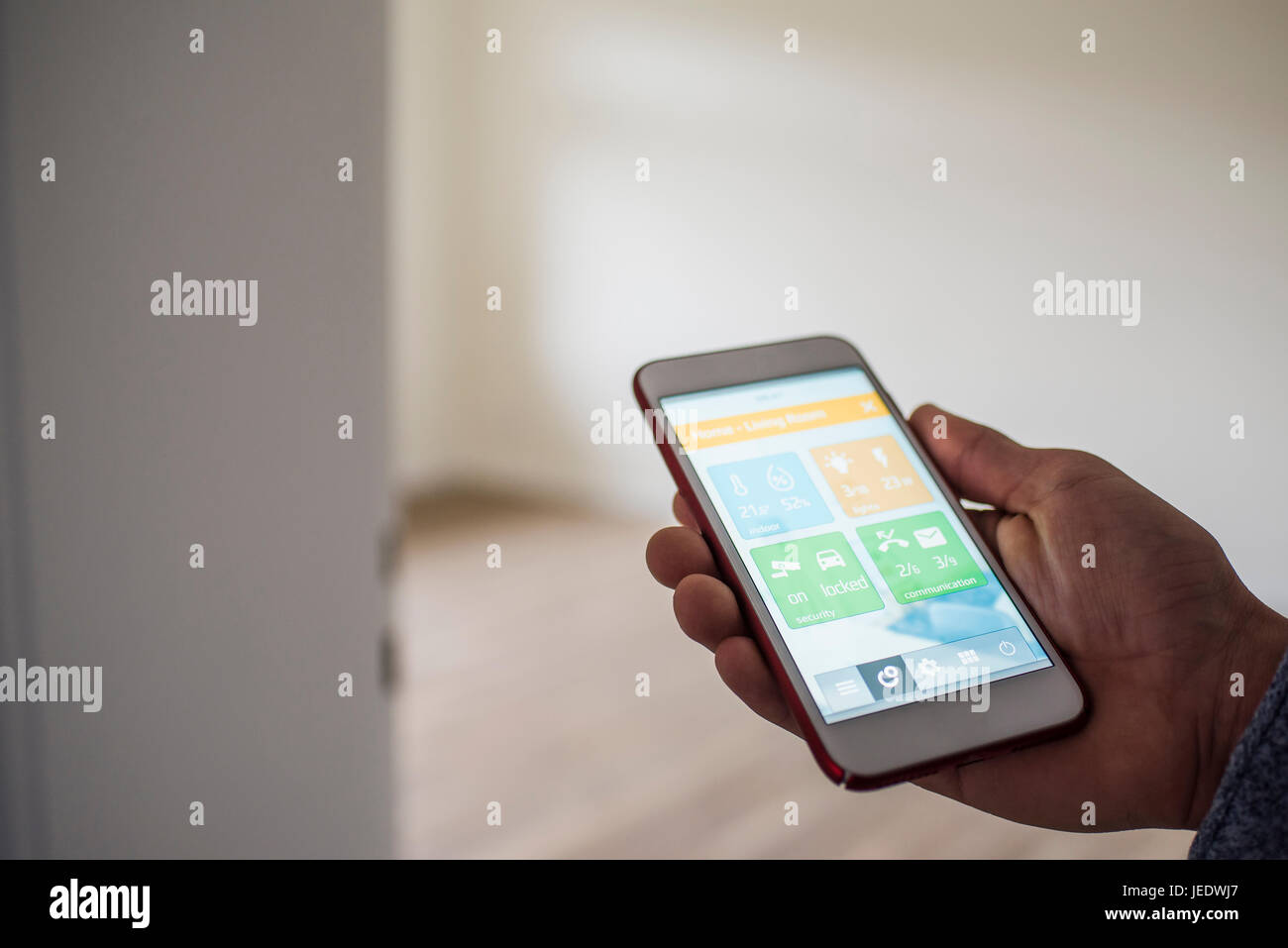 Man at home holding smartphone with smart home apps Stock Photo