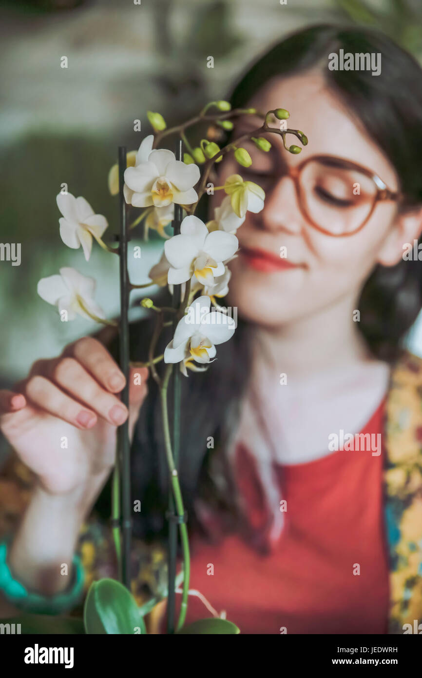 Young woman taking care of her orchid at home Stock Photo