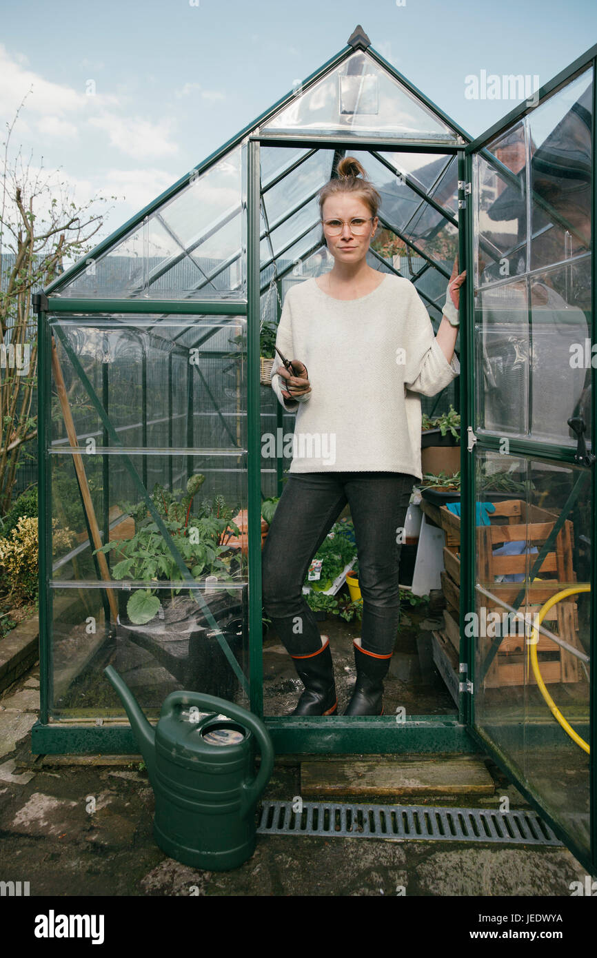 Young woman standing in her greenhouse Stock Photo - Alamy