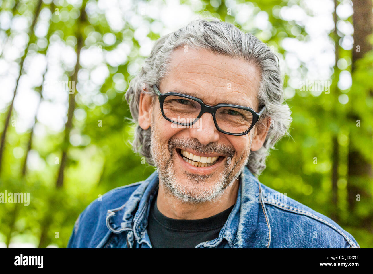 Portrait of laughing man with grey hair and beard wearing glasses Stock Photo