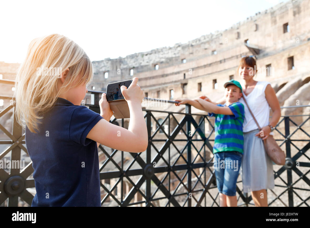 Italy, Rome, little girl taking picture of mother and brother with smartphone Stock Photo
