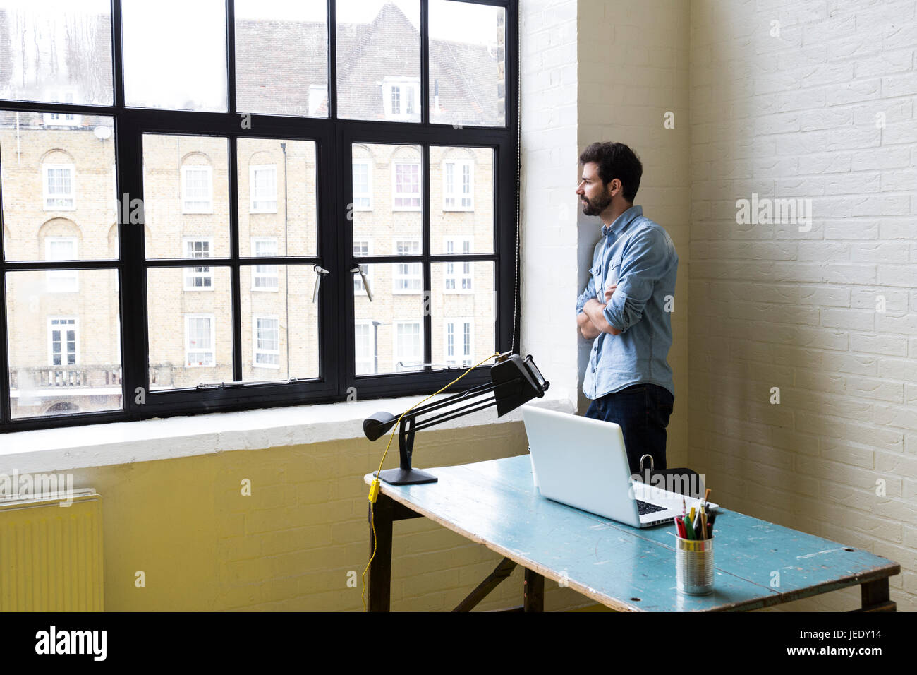 Man leaning against a wall looking out of window Stock Photo