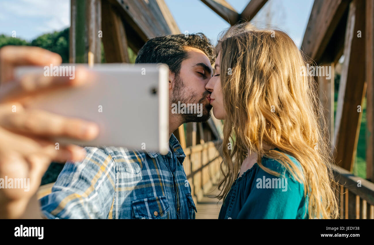 Couple in love taking selfie with smartphone while kissing Stock Photo ...