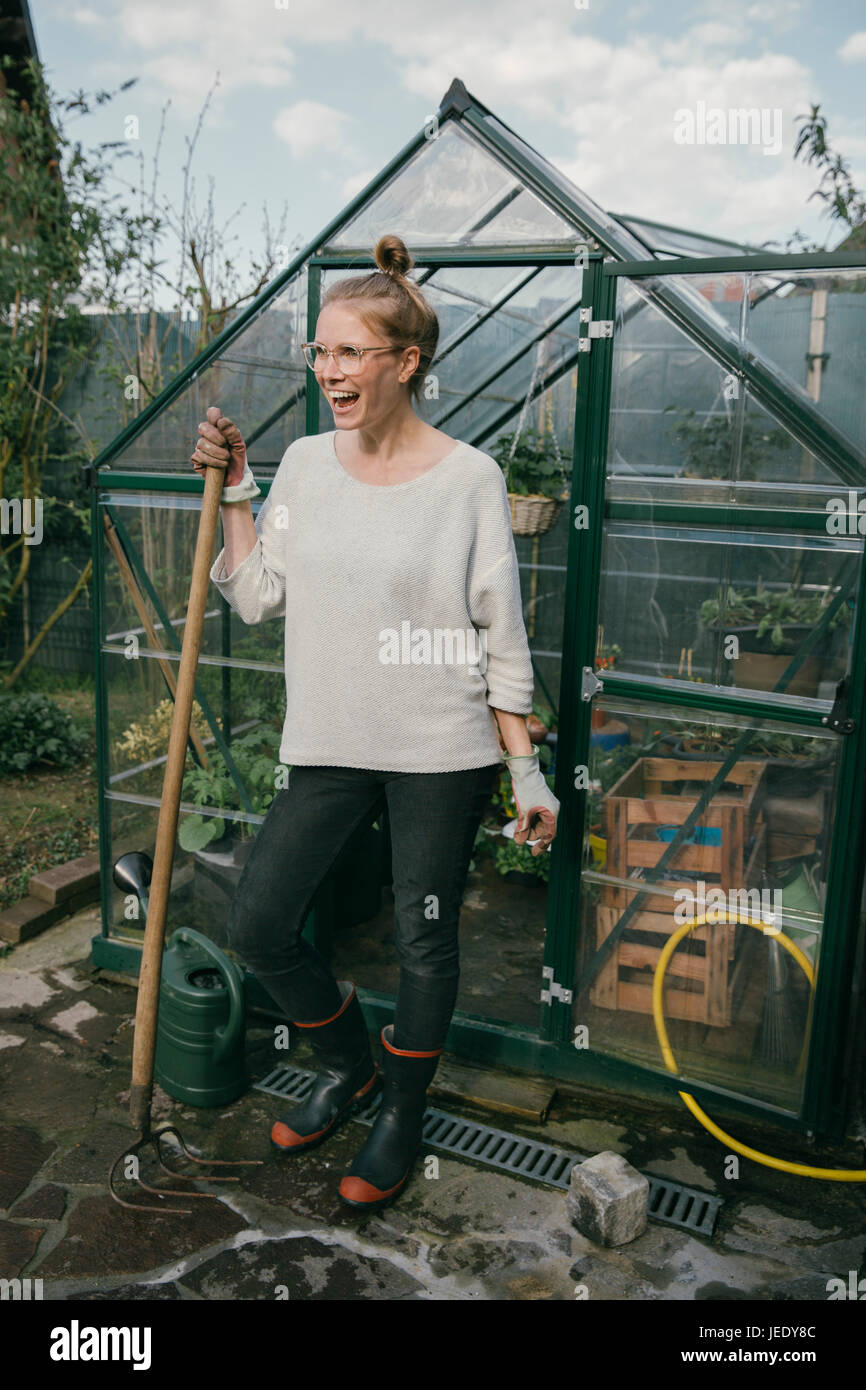 Happy young woman standing in front of greenhouse Stock Photo - Alamy