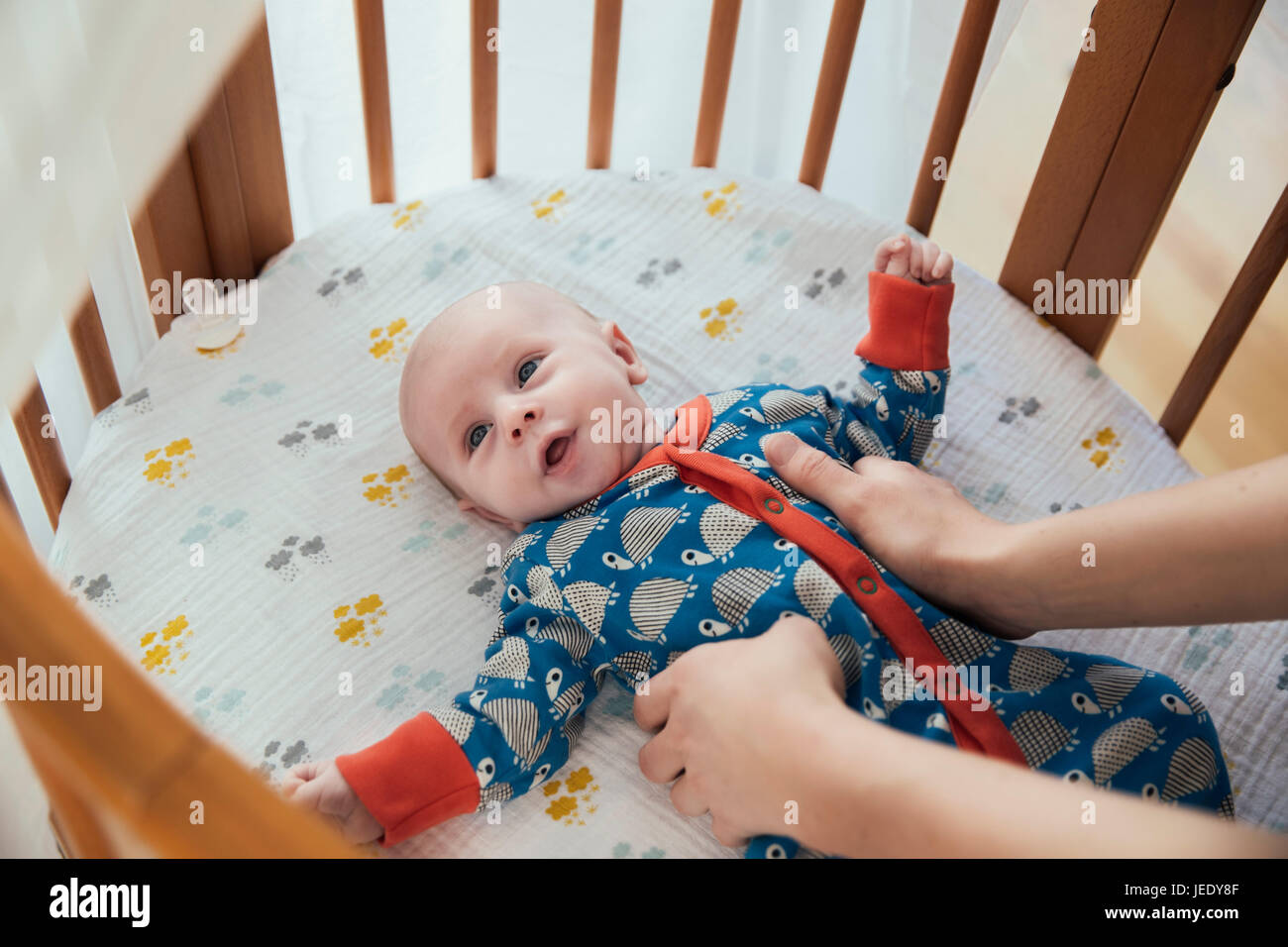 Mother putting her newborn baby boy into crib Stock Photo Alamy