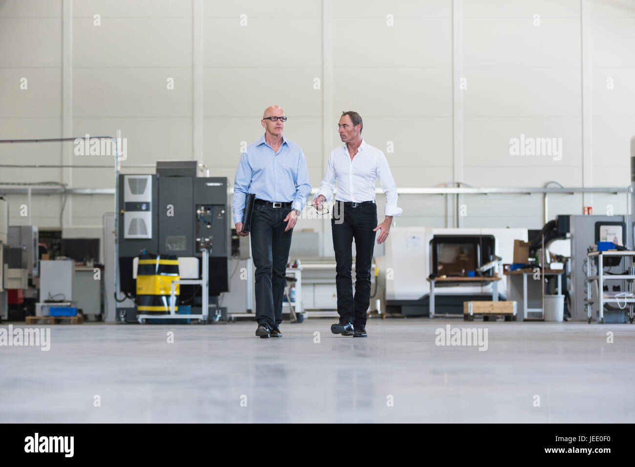 Two businessmen walking and talking in factory shop floor Stock Photo ...