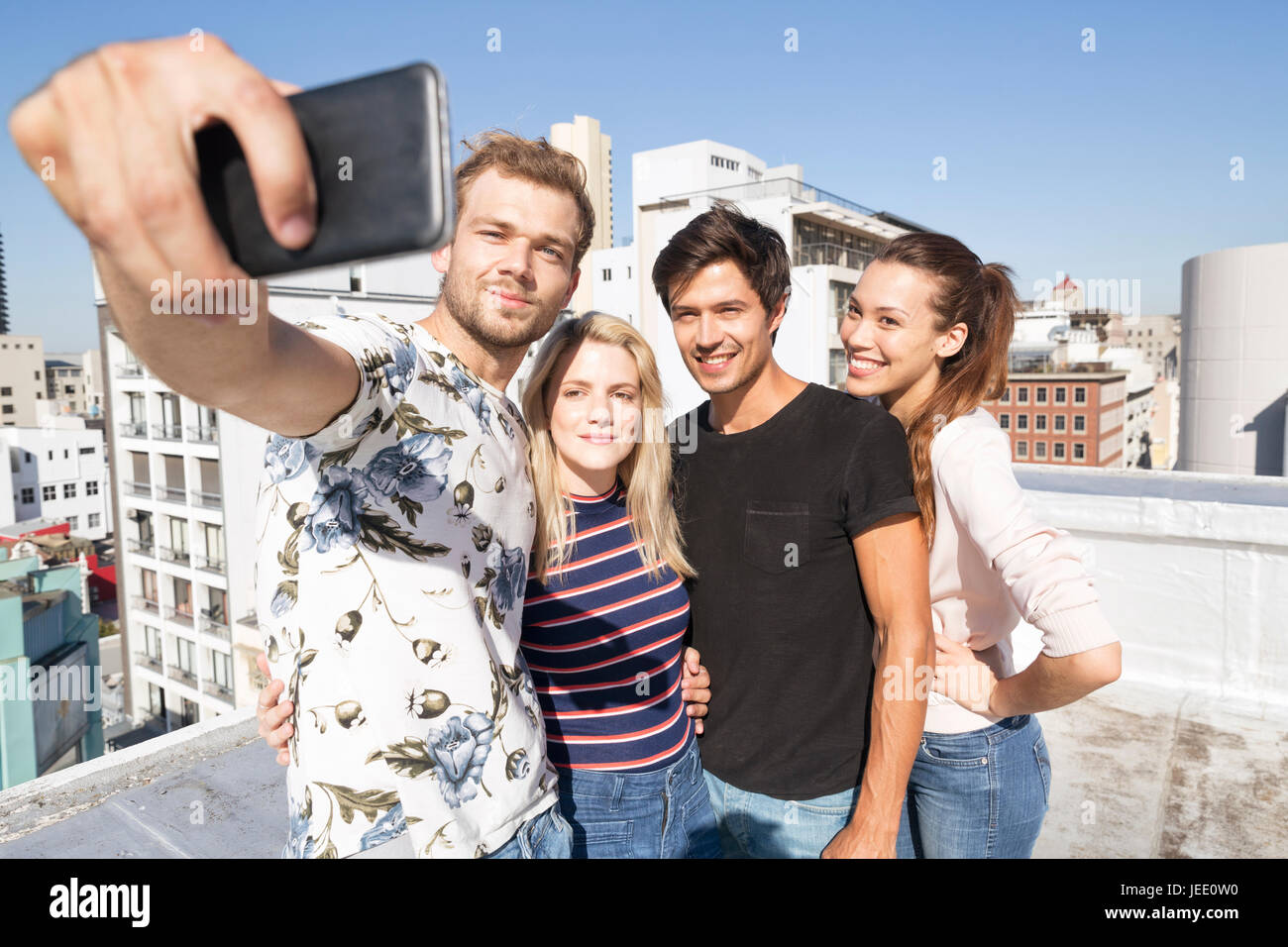 Friends taking selfies on a rooftop terrace Stock Photo