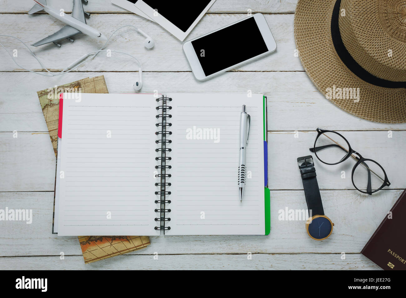 Top view accessoires to travel concept.Notebook free space for writing with pen on white table backgroun.Items is map,watch,eyeglasses,passport,hat,mo Stock Photo