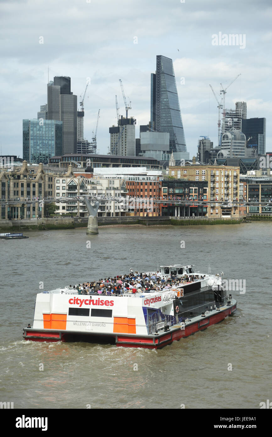 A large tourist boat on the River Thames sails towards the City of London. Shows the Millennium Bridge and the 'Cheese-grater' tower in the background Stock Photo