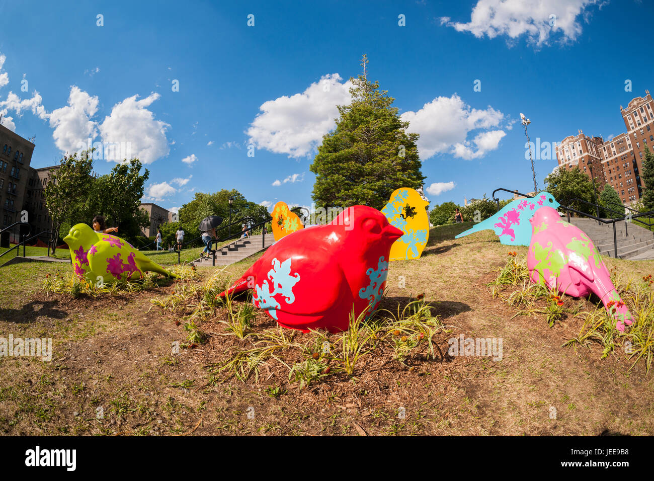 Visitors to Joyce Kilmer Park in the Bronx in New York on Tuesday, June 20, 2017 enjoy 'Flying High for Equality' by the artists Patricia Cazoria and Nancy Saleme. The oversized colorful sparrows represented by the artwork are meant to be a metaphor for the search for equality, channeling the urban sparrow's abilities of resistance, intelligence and beauty represented in New York's communities.  The sculpture is funded by the Art in the Parks: UNIQLO Park Expressions Grant.  (© Richard B. Levine) Stock Photo