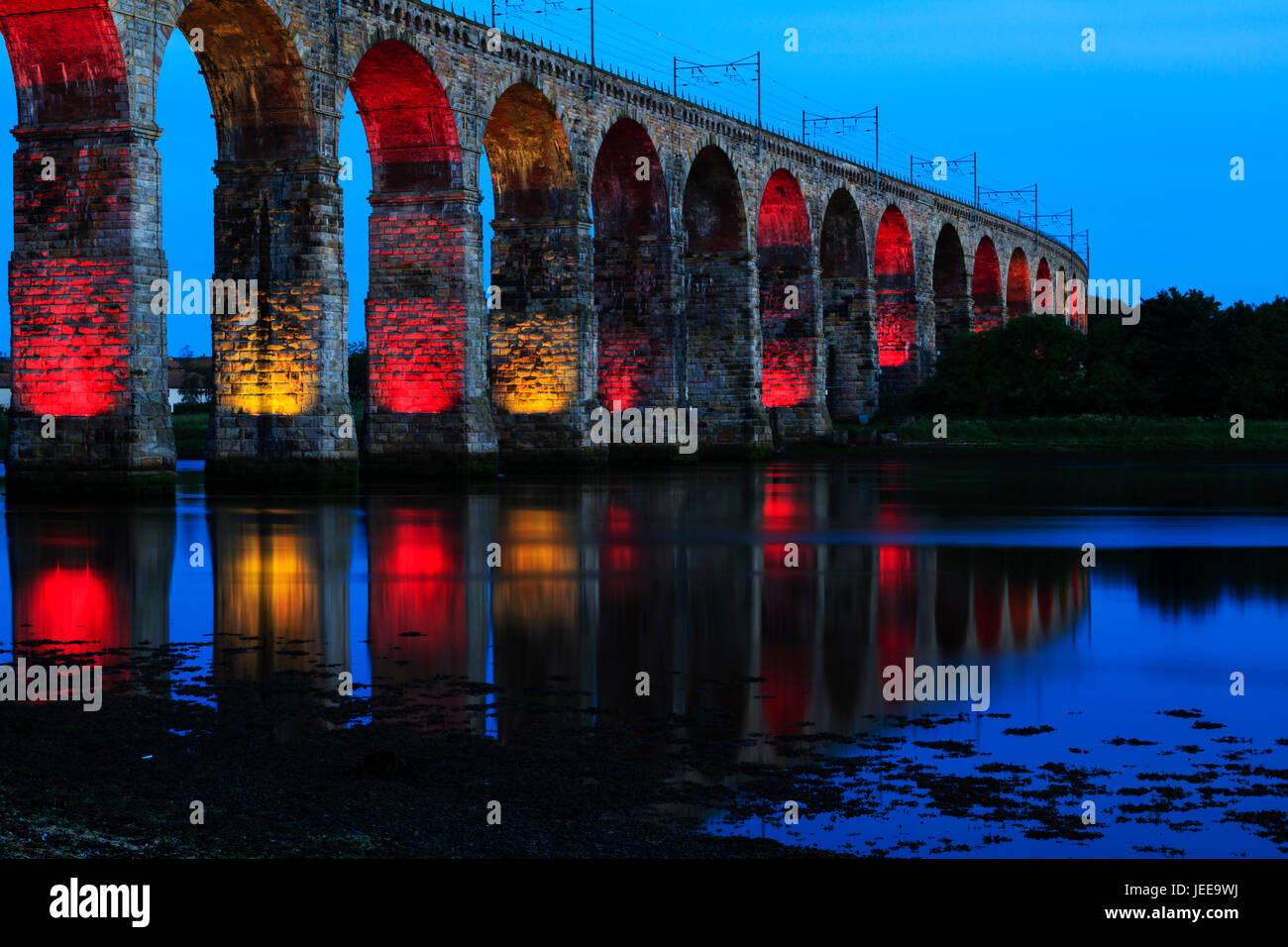 The Royal Border Railway bridge, Berwick upon Tweed, lit up at night in red and yellow. Northumberland, England. Stock Photo