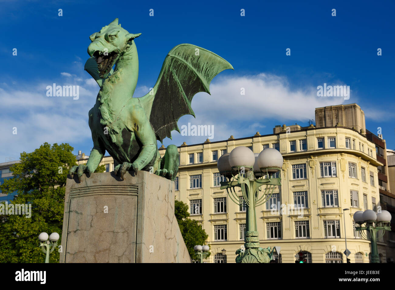 Green copper Dragon statue on concrete pedestal of Dragon Bridge over the Ljubljanica river symbol of Ljubljana Slovenia with lamp posts Stock Photo