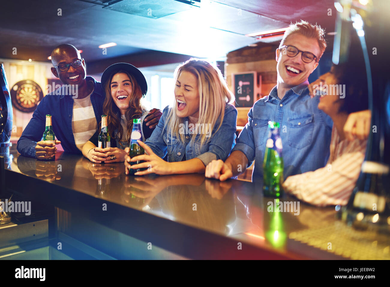 Horizontal indoors shot of laughing out loud group of people at the bar counter. Stock Photo