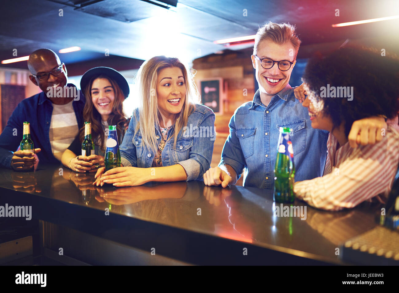 A group of young cheerful people talking while spending time in the bar. Stock Photo