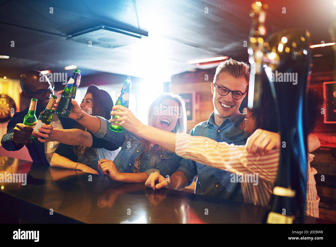 Laughing people holding up the beer bottles in the bar. Friends and fun concept. Stock Photo
