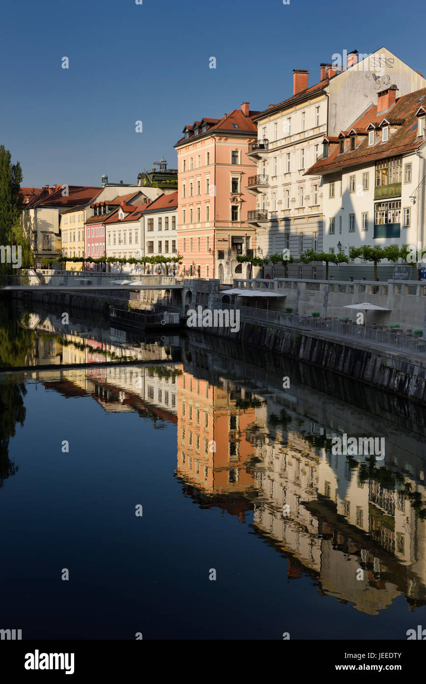 Bright buildings at the Ribja Brv modern footbridge reflected in the calm Ljubljanica river canal in Ljubljana Slovenia Stock Photo