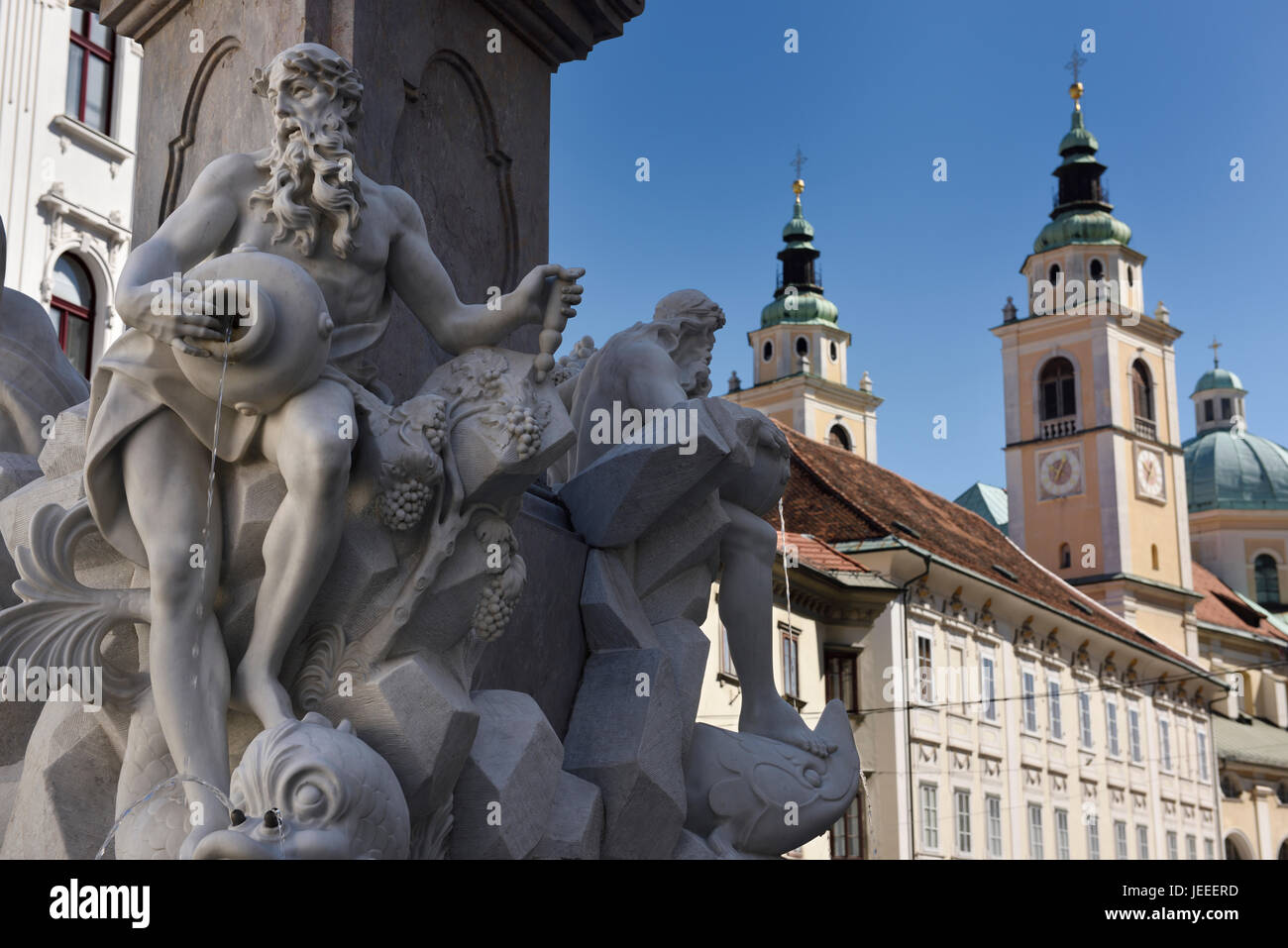 Detail of the Robba marble scultpure on The Fountain of the Three Rivers at Town Square Ljubljana Slovenia with St Nicholas church Cathedral Stock Photo