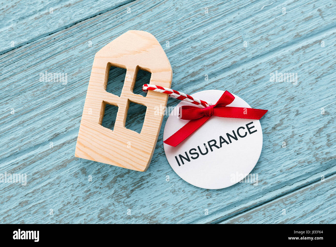 Home insurance concept with wood house and paper insurance tag Stock Photo