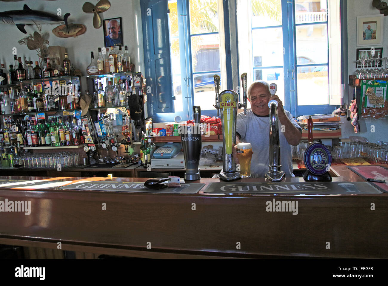 Barman pulling pints of beer Inside Gleneagles Bar pub at Mgarr, Gozo, Malta Stock Photo