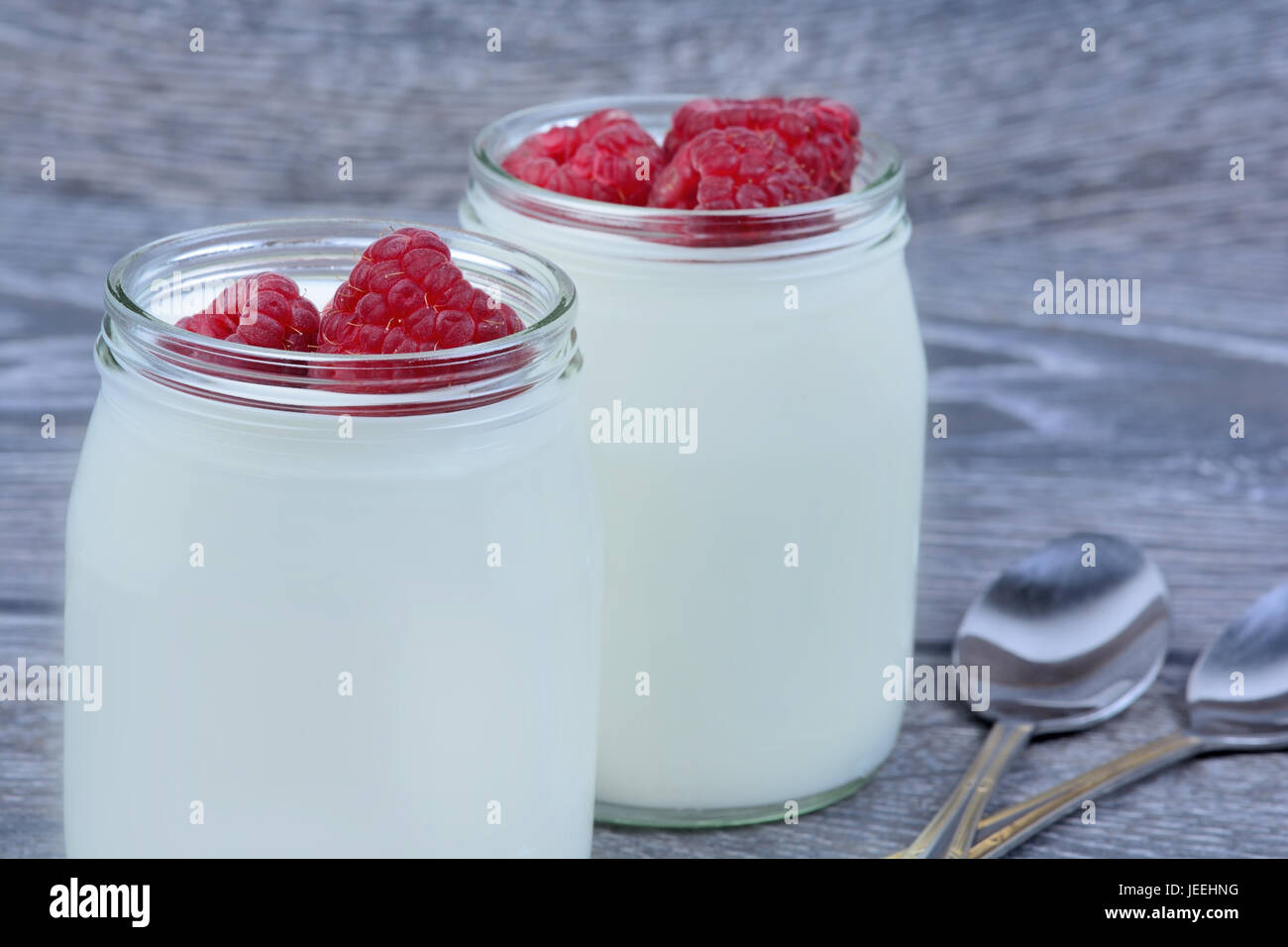 Yogurt with raspberry in a jars on wooden table Stock Photo