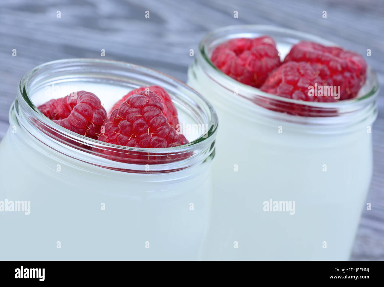 Raspberry with yogurt in a jars on table closeup Stock Photo