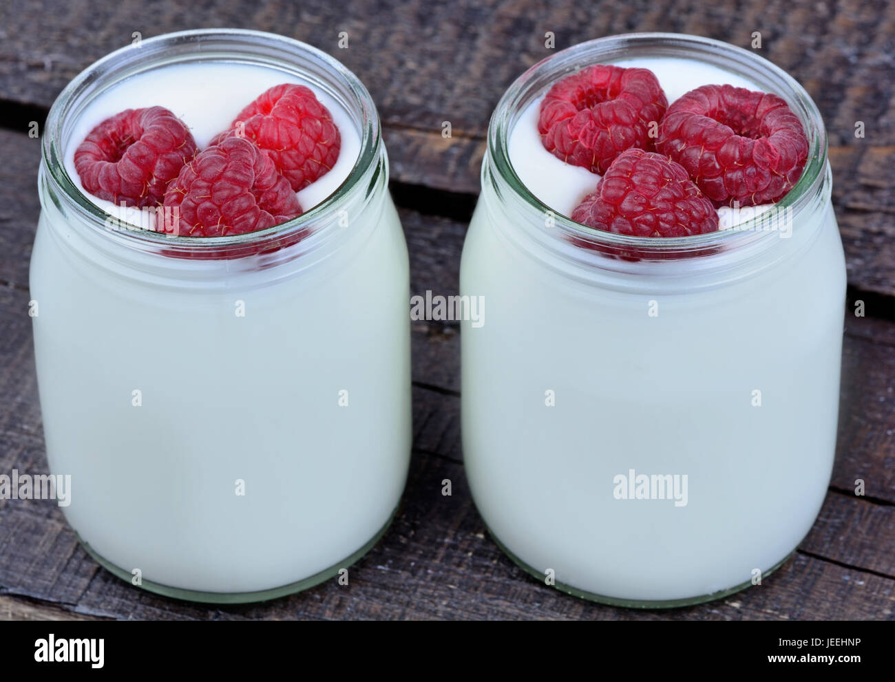 Raspberry with yogurt in a jars on table Stock Photo