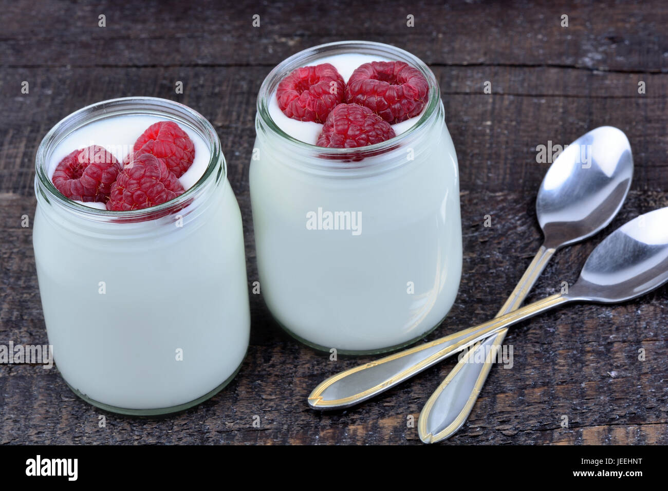 Raspberry with yogurt in a jars on wooden table Stock Photo